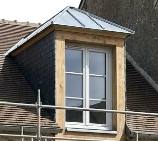 Lucarne restaurée avec jouées en ardoise et couverture en zinc sur une maison ancienne de Fontainebleau